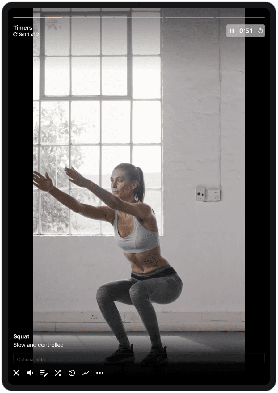 A follow-along squat workout playing on an iPad, with set timers, exercise name, and playback controls